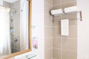 A bathroom with a shower, a glass shelf, a towel rack with two towels, and a mirror. - Majestic Hotel (formerly Octagon Mansion Hotel) (Manila)