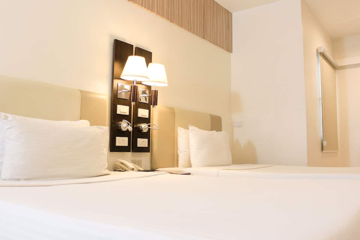 A hotel room with a large bed, two bedside lamps, a phone, and a wall-mounted light fixture.
