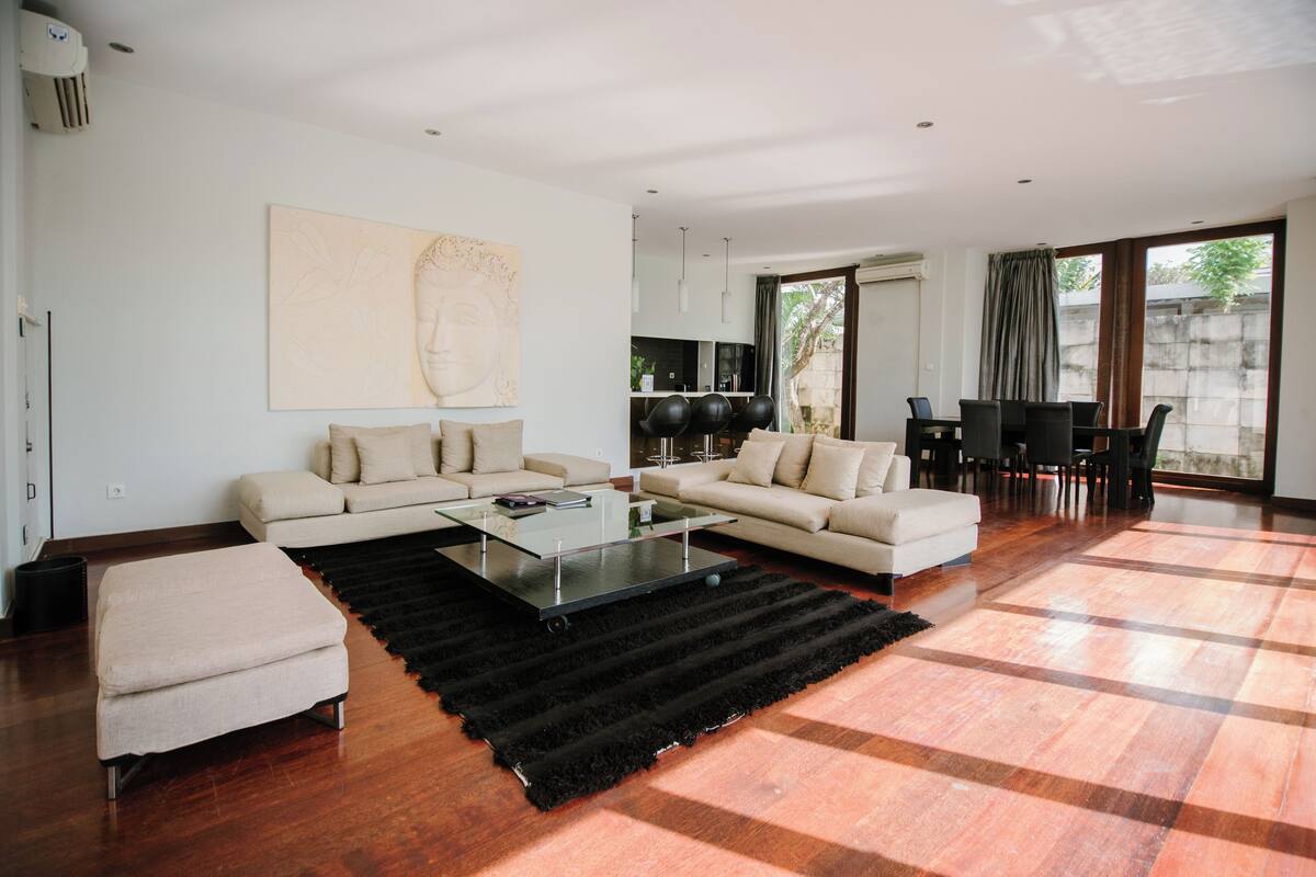 Uma sala de estar ampla com dois sofás, uma mesa de centro e um espaço de jantar com cadeiras.