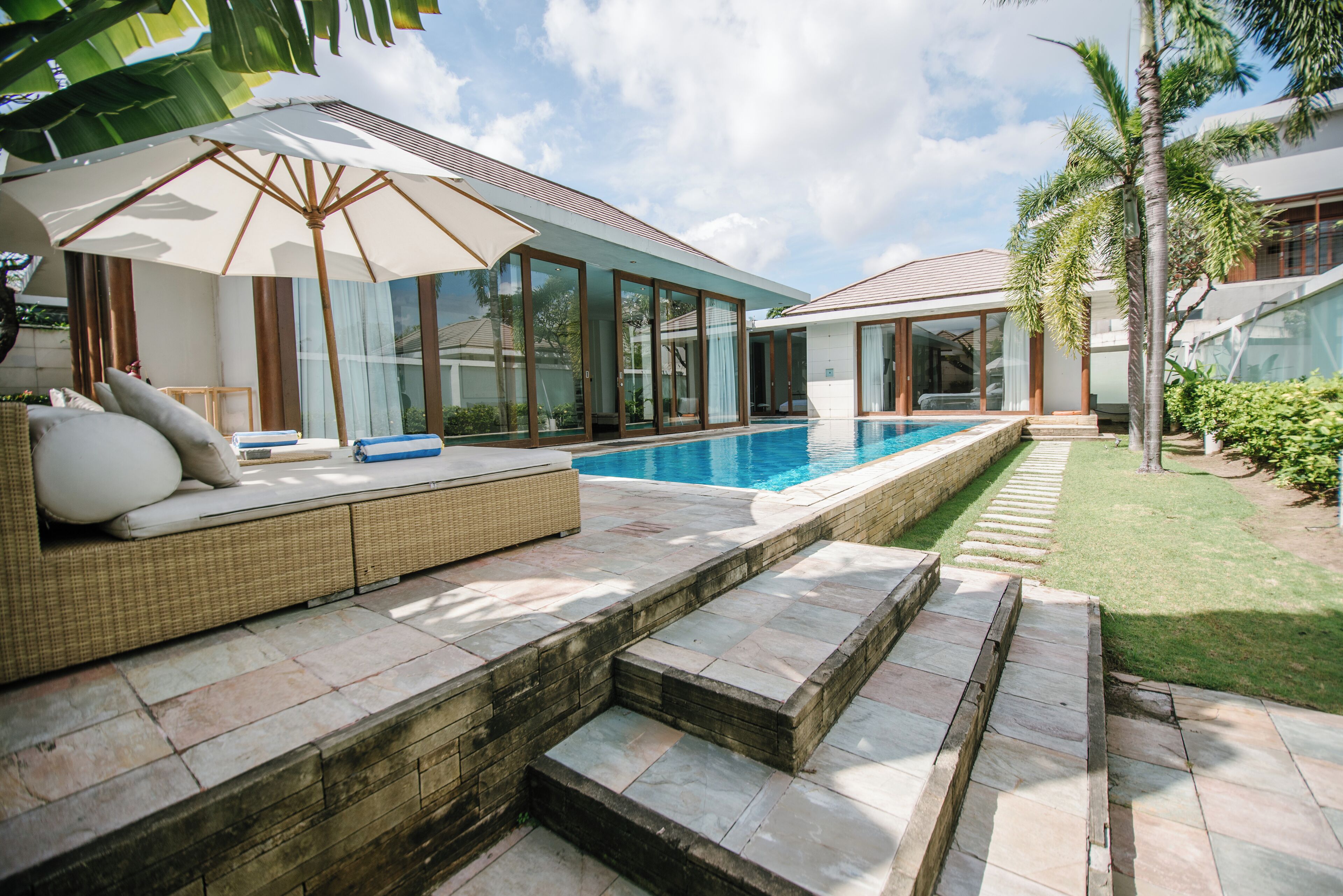 A modern outdoor pool area with a built-in seating area, a clear view of the pool, and a well-maintained lawn.