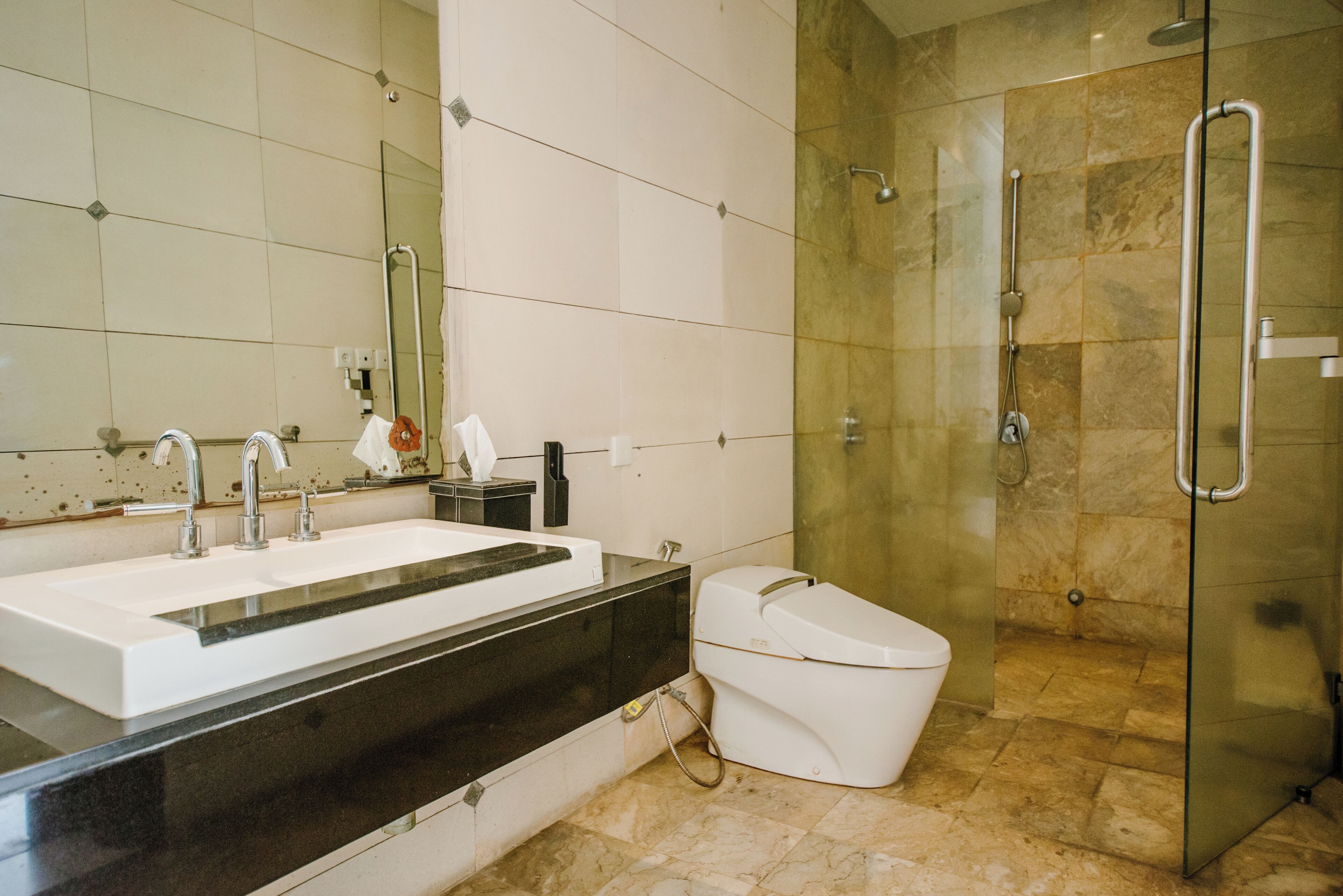A modern bathroom with a large white sink, a glass shower enclosure, and a white toilet.