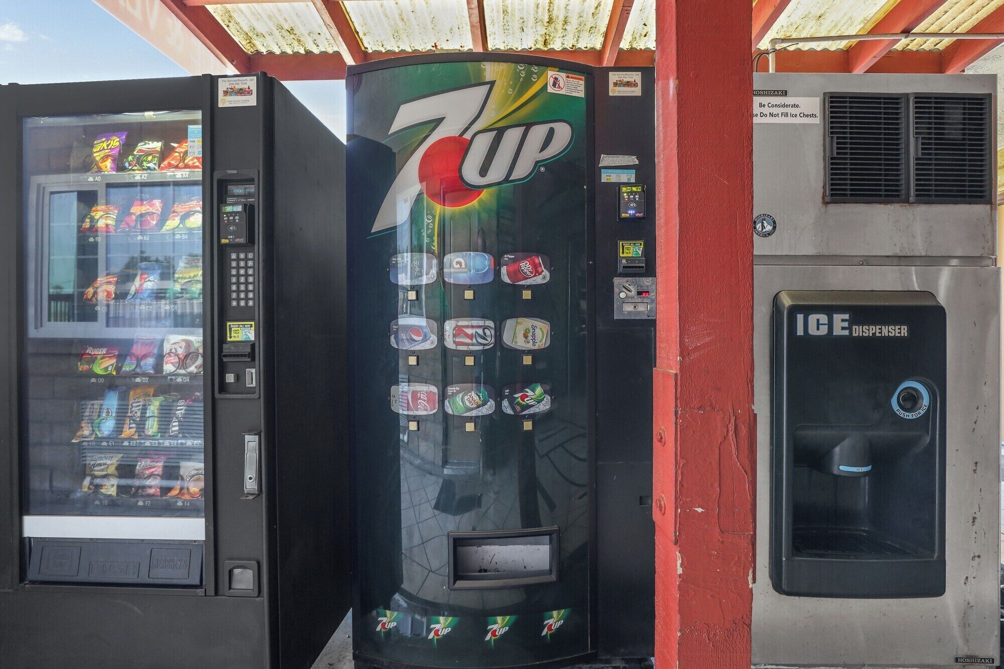 A 7UP vending machine with a selection of snacks and a push button for ice.