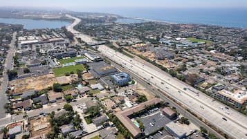 Vue aérienne d’une zone urbaine côtière, avec une grande autoroute, des immeubles résidentiels et une vaste étendue d’eau.