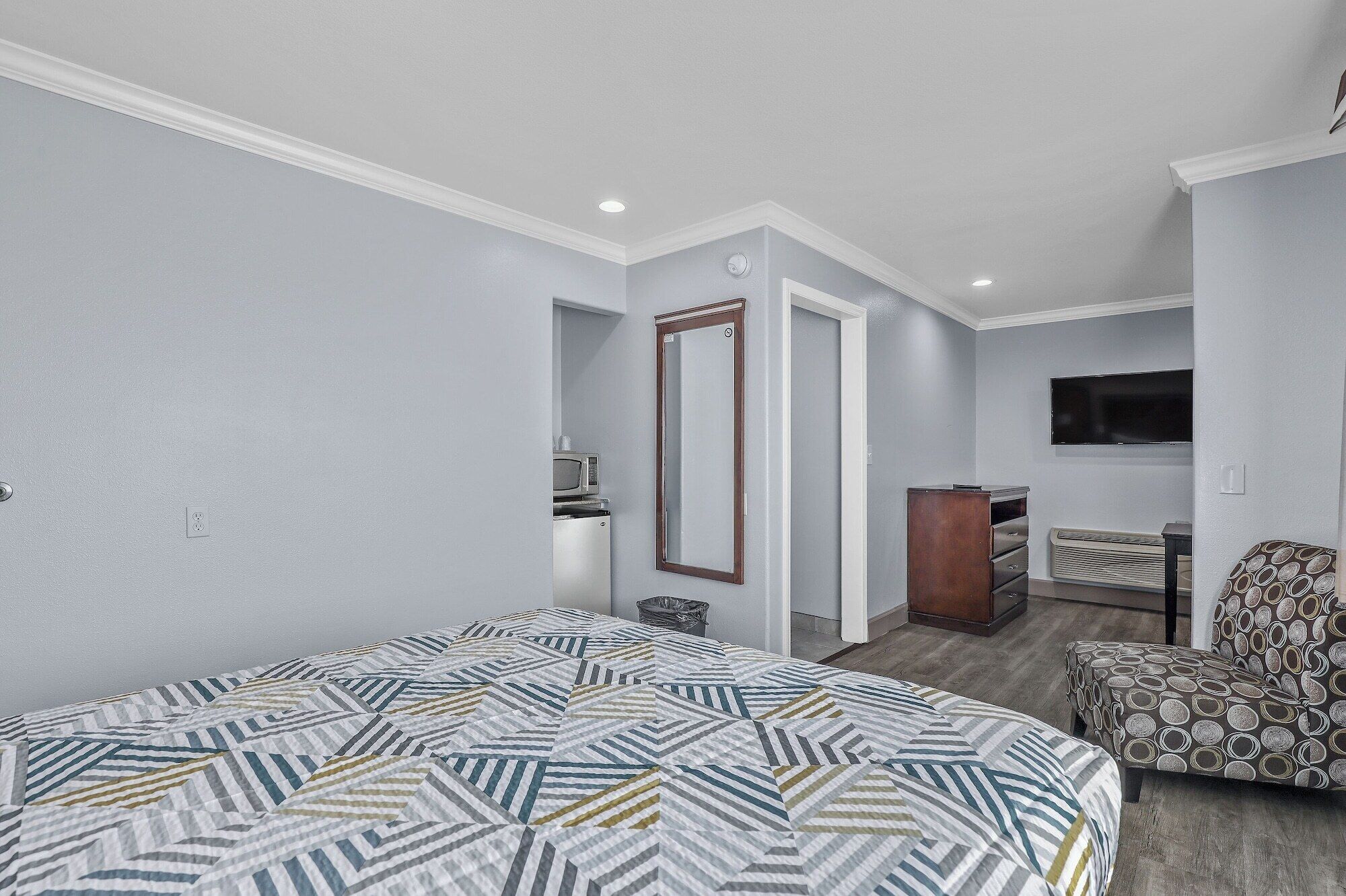 A bedroom with a bed, a dresser, a chair, and a television.