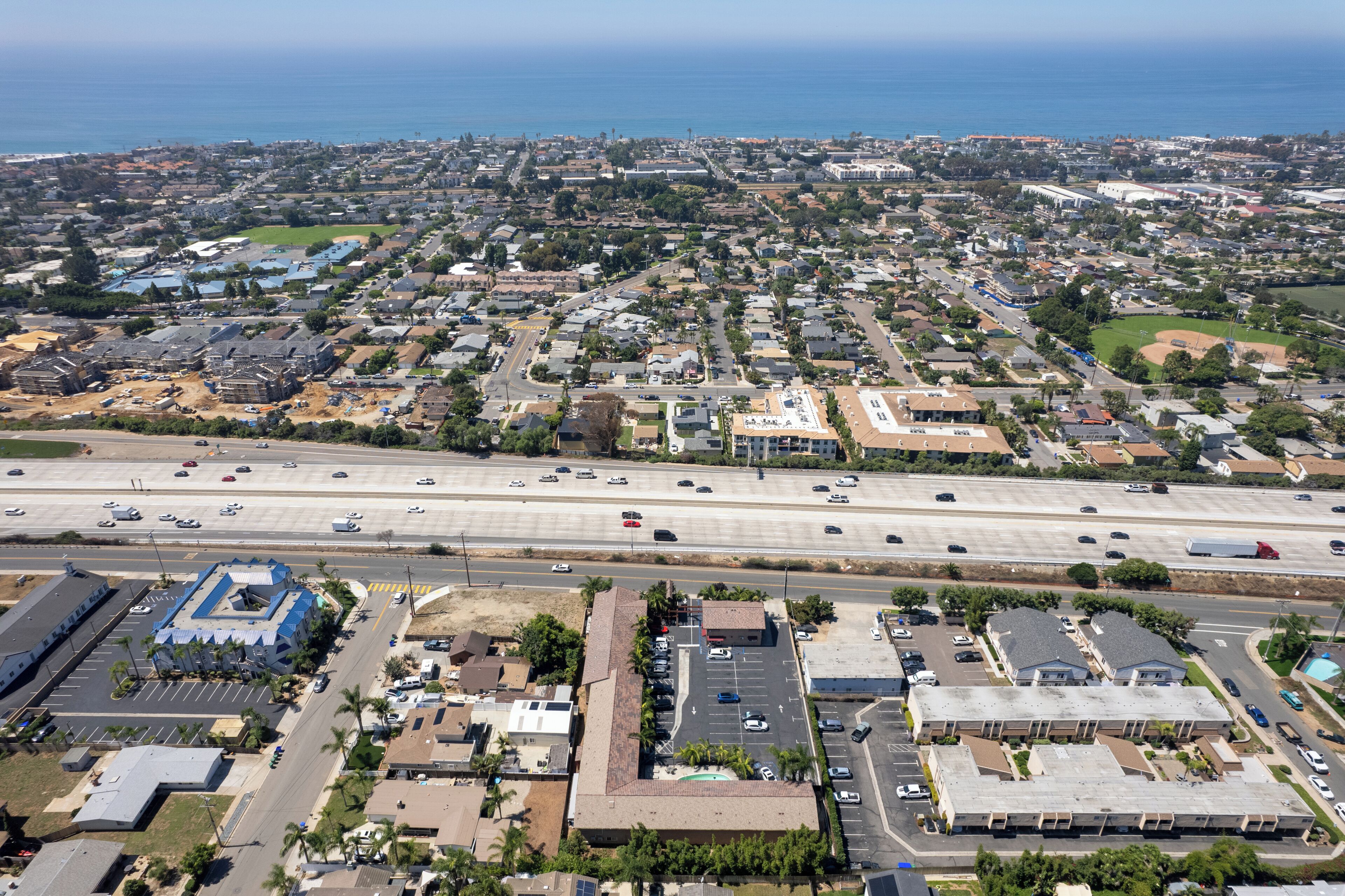 An aerial view of a residential area with a highway, parking lots, and buildings.