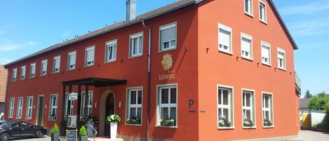 A red building with multiple windows and a sign that reads "Löwen Hotel Restaurant".