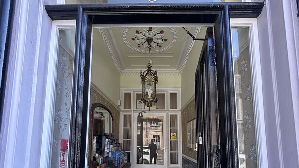 The entrance to Regent House Hotel with a black door, a blue mat, and a sign above the door.