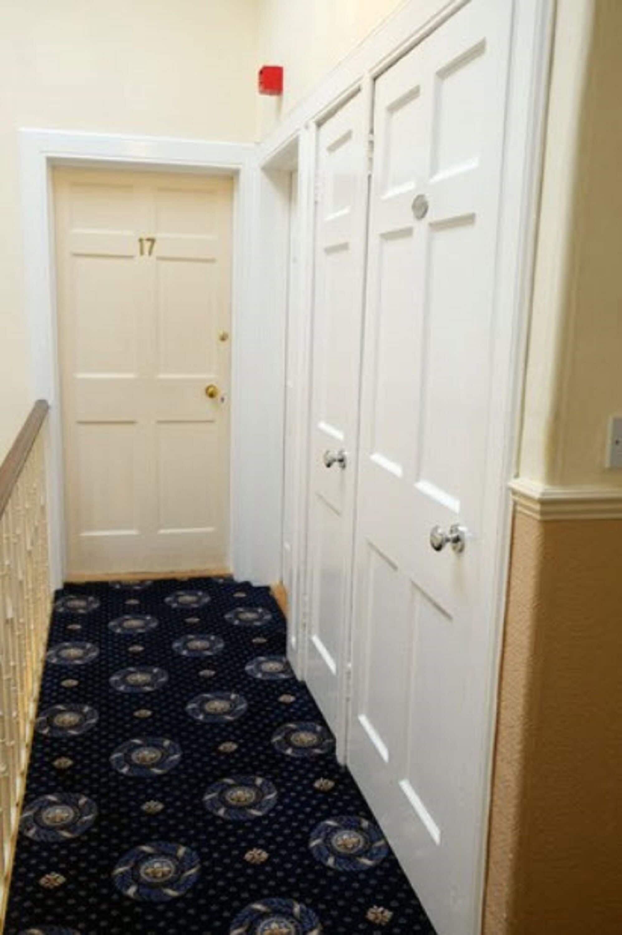 A narrow hallway with a patterned carpet, white doors, and a visible room number 17.