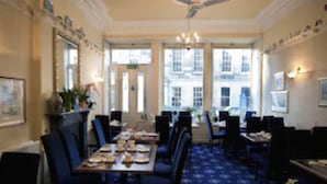 A dining area with a long table, chairs, and a patterned carpet.