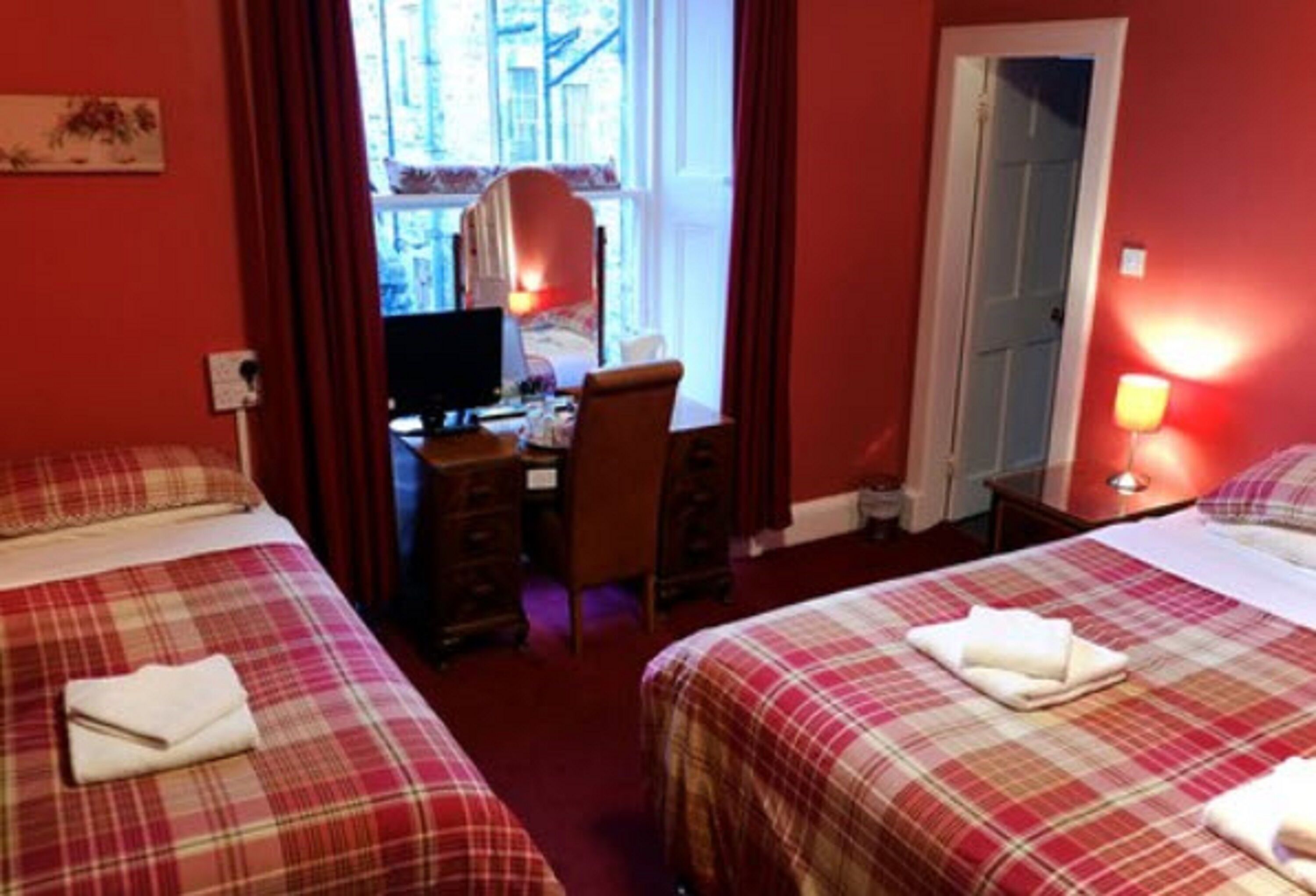 A hotel room with two beds, a desk, and a computer.