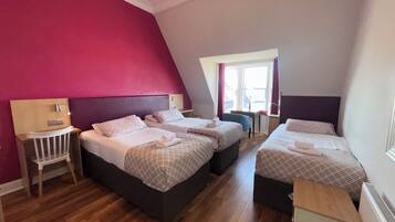 Een hotelkamer met twee bedden, een tafeltje en een raam met gordijnen.