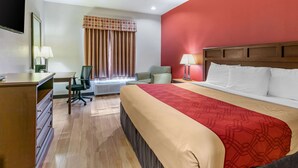 Une chambre d’hôtel avec un lit, un bureau, une chaise et une fenêtre avec des rideaux.
