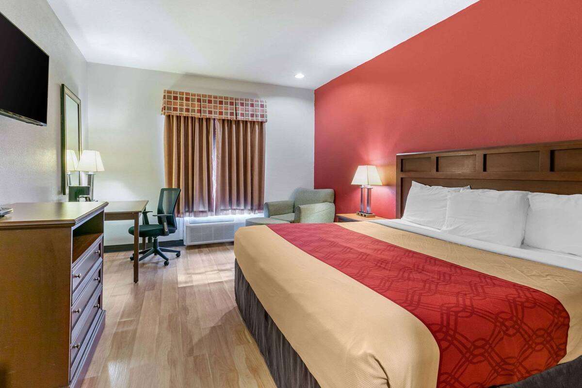Una habitación de hotel con cama, escritorio, silla y televisor.