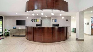 A reception area with a curved wooden desk, two computer monitors, and a flat-screen TV mounted on the wall. - Best Western Plus Daphne Inn & Suites (Daphne)