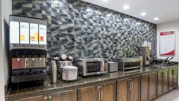 A commercial kitchen with a coffee machine, microwave, and stainless steel appliances.