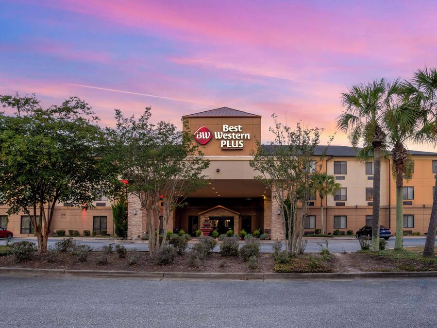 A Best Western Plus hotel with a prominent sign, surrounded by landscaped greenery and palm trees.