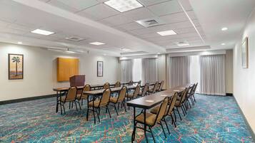 A conference room with a long table, chairs, and a patterned carpet.