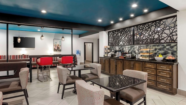 A modern restaurant with a blue ceiling, a kitchen area, and seating arrangements. - Best Western Plus Daphne Inn & Suites (Daphne)