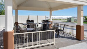 An outdoor patio with two barbecue grills, a table, and chairs. - Candlewood Suites Cheyenne by IHG (Cheyenne)