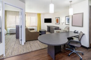 A hotel room with a large conference table, a sofa, a desk, and a television. - Candlewood Suites Cheyenne by IHG (Cheyenne)