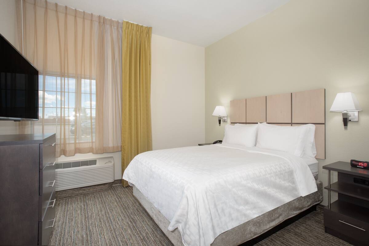 A hotel room with a bed, a TV, a desk, and a lamp.