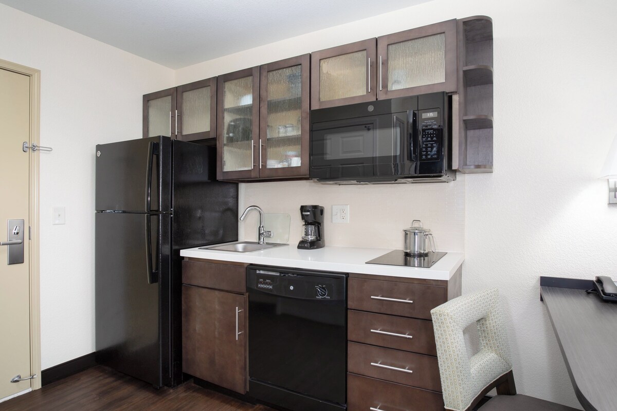 A compact kitchen with a refrigerator, microwave, coffee maker, and dishwasher.
