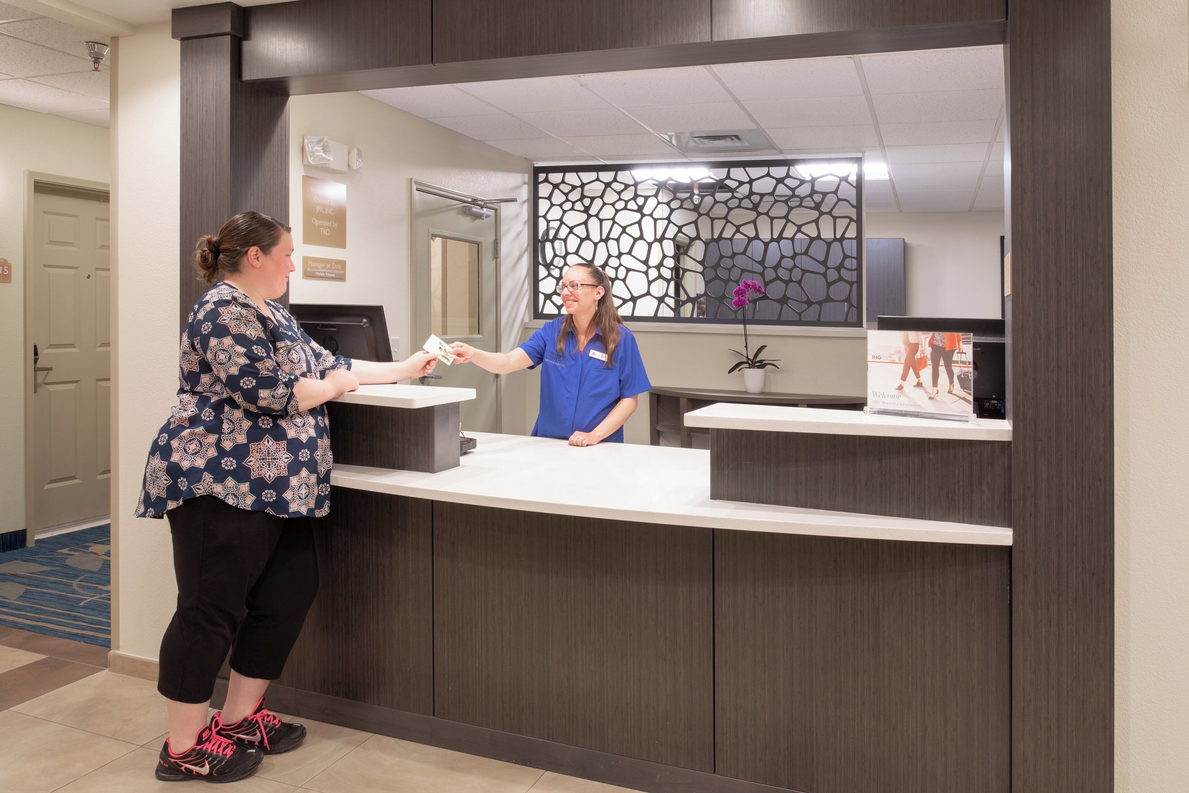 A reception desk with a receptionist and a guest.