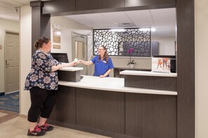 A reception desk with a receptionist and a guest. - Candlewood Suites Cheyenne by IHG (Cheyenne)