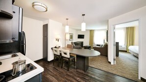 A modern hotel room with a kitchenette, a dining area, a living area with a sofa and TV, and a bedroom with a bed and curtains. - Candlewood Suites Cheyenne by IHG (Cheyenne)