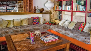 Una sala de estar acogedora con un sofá, una mesita de centro con libros y objetos decorativos, una estantería y un espejo grande.