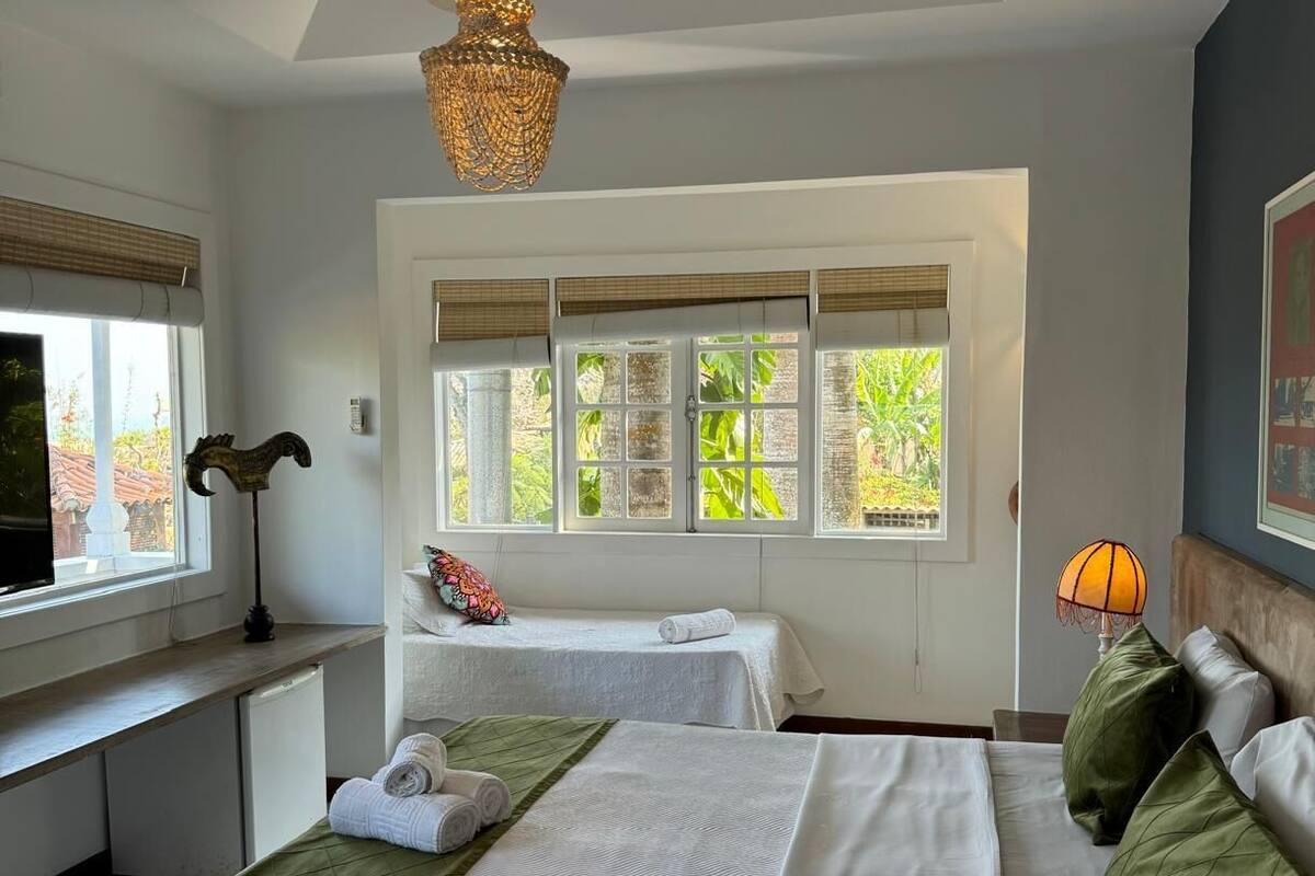 Un dormitorio con dos camas, un escritorio y una ventana con vistas a zonas verdes.