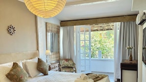 Un dormitorio amplio con una cama grande, una lámpara colgante, una silla y vistas a zonas verdes.