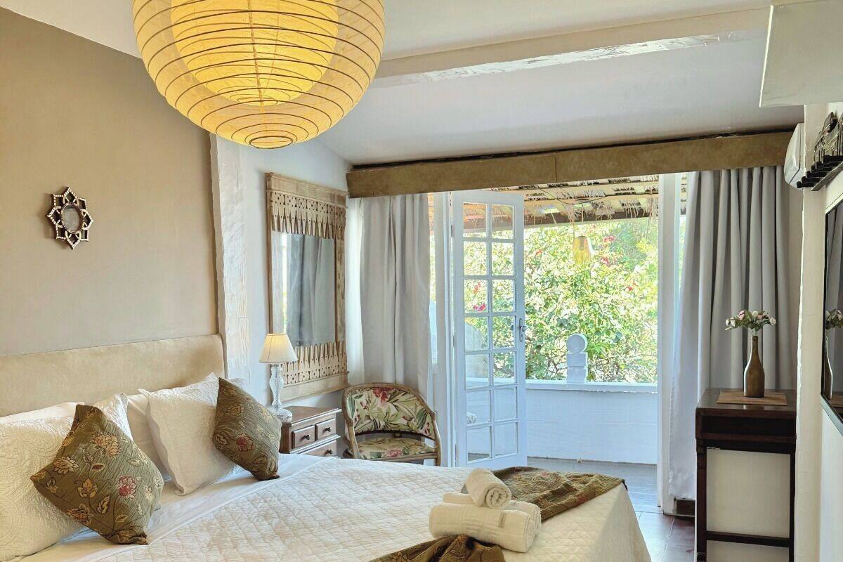 Un dormitorio amplio con una cama grande, una lámpara colgante, una silla y vistas a zonas verdes.