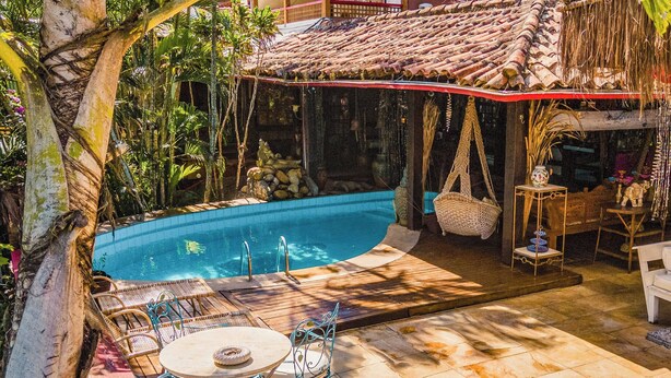 Un área de piscina con solárium empinado, sillas de descanso y una mesa con sillas.
