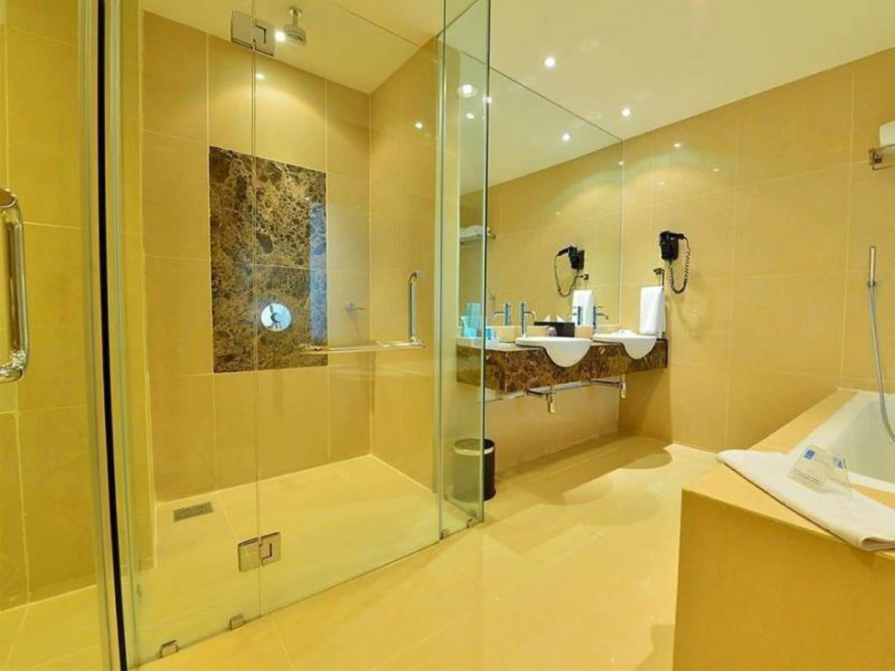 Ein modernes Badezimmer mit einer Duschkabine aus Glas, einer Marmor-Spritzschutzwand und zwei Waschbecken mit Spiegel darüber.