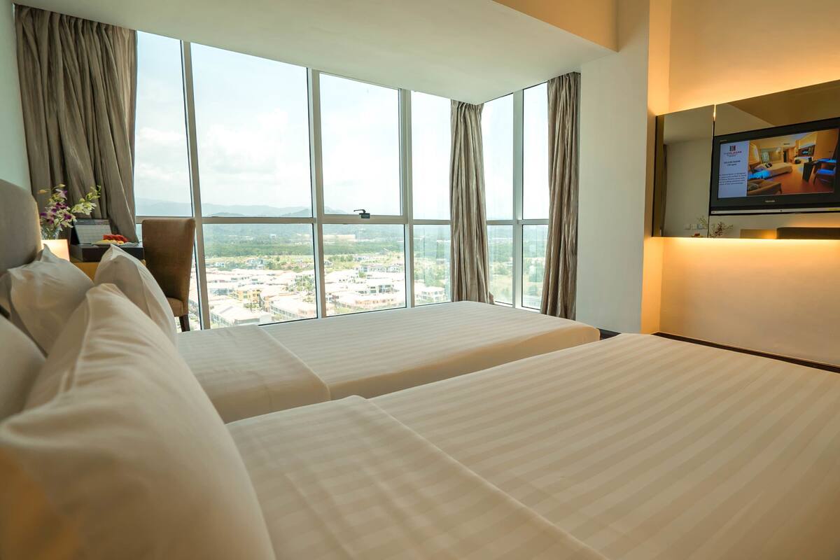 A hotel room with two beds, a TV on the wall, and a large window offering a city view.