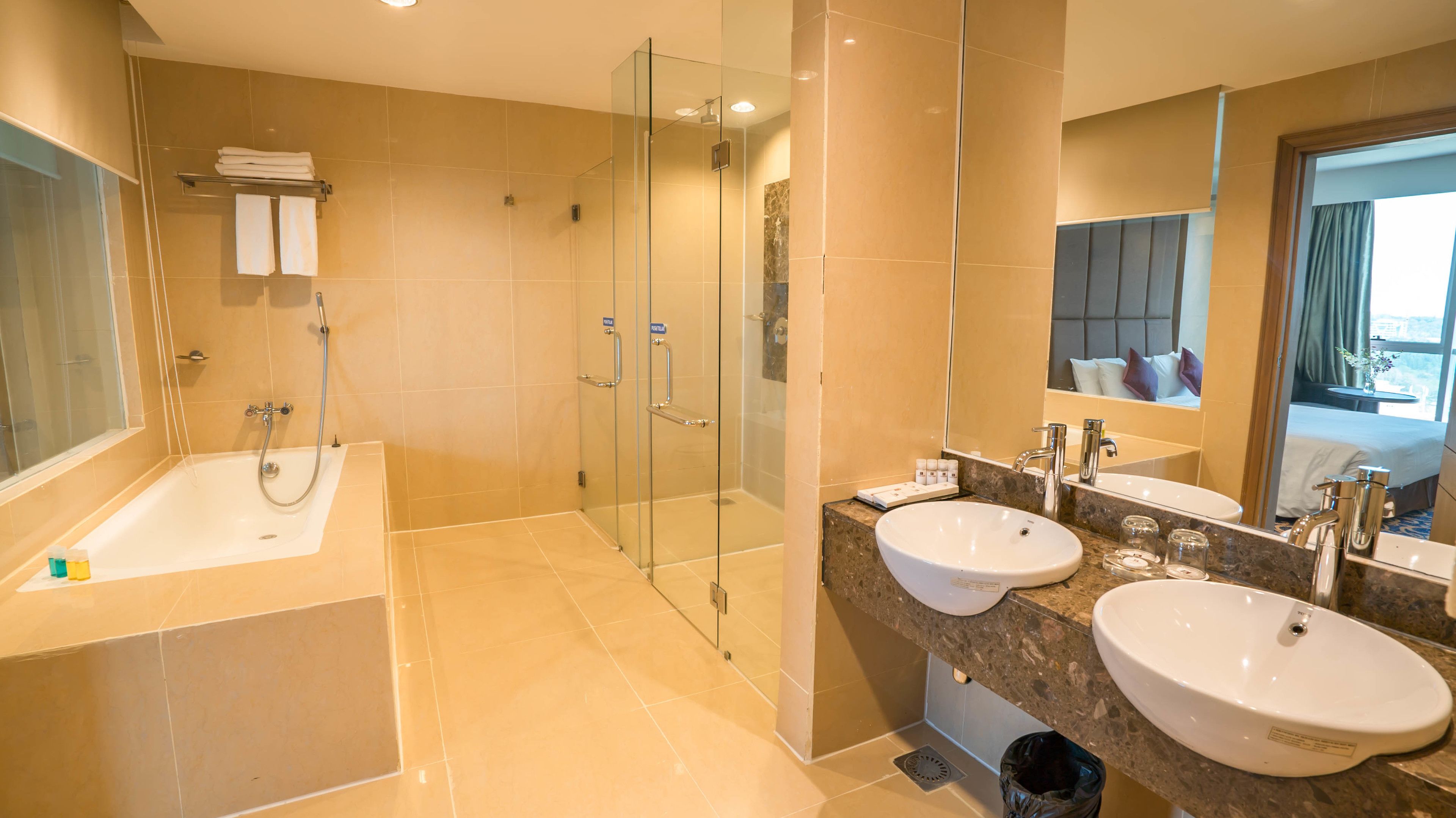 Un baño moderno con bañera, dos lavamanos, ducha con mampara de vidrio y un espejo grande.