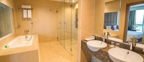 Un baño moderno con bañera, dos lavamanos, ducha con mampara de vidrio y un espejo grande.