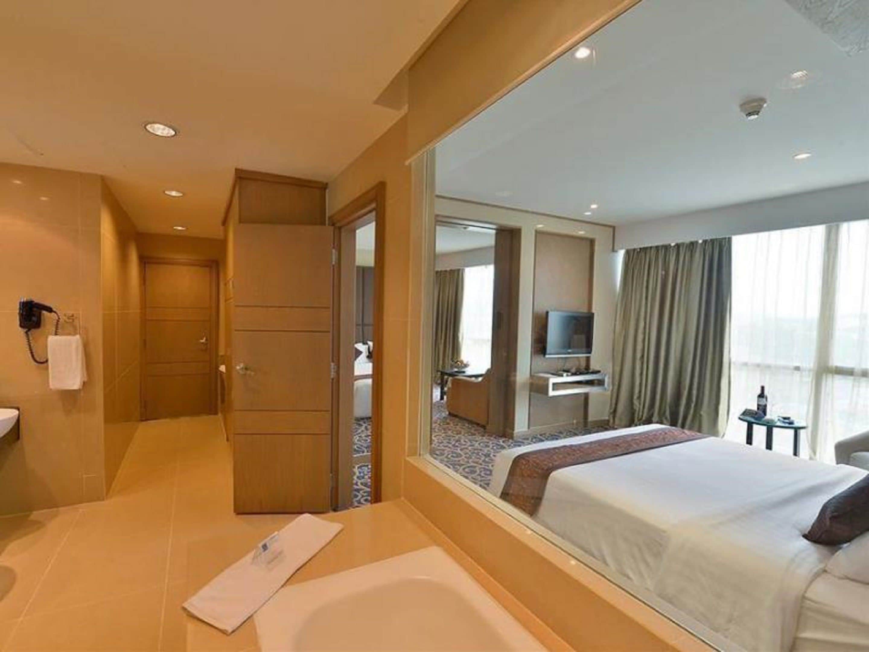A hotel room with a large bed, a bathroom with a bathtub, a television, and a desk.