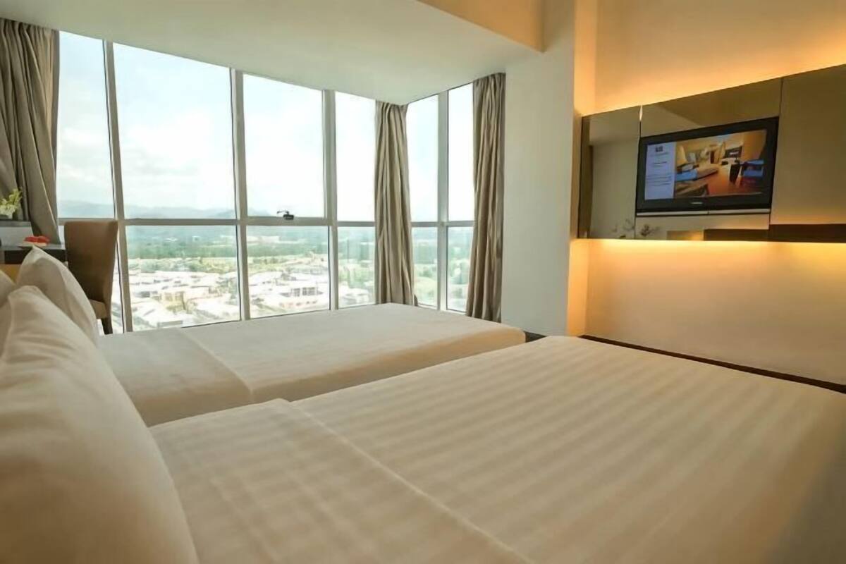 A hotel room with two beds, a TV on the wall, and a large window with a city view.