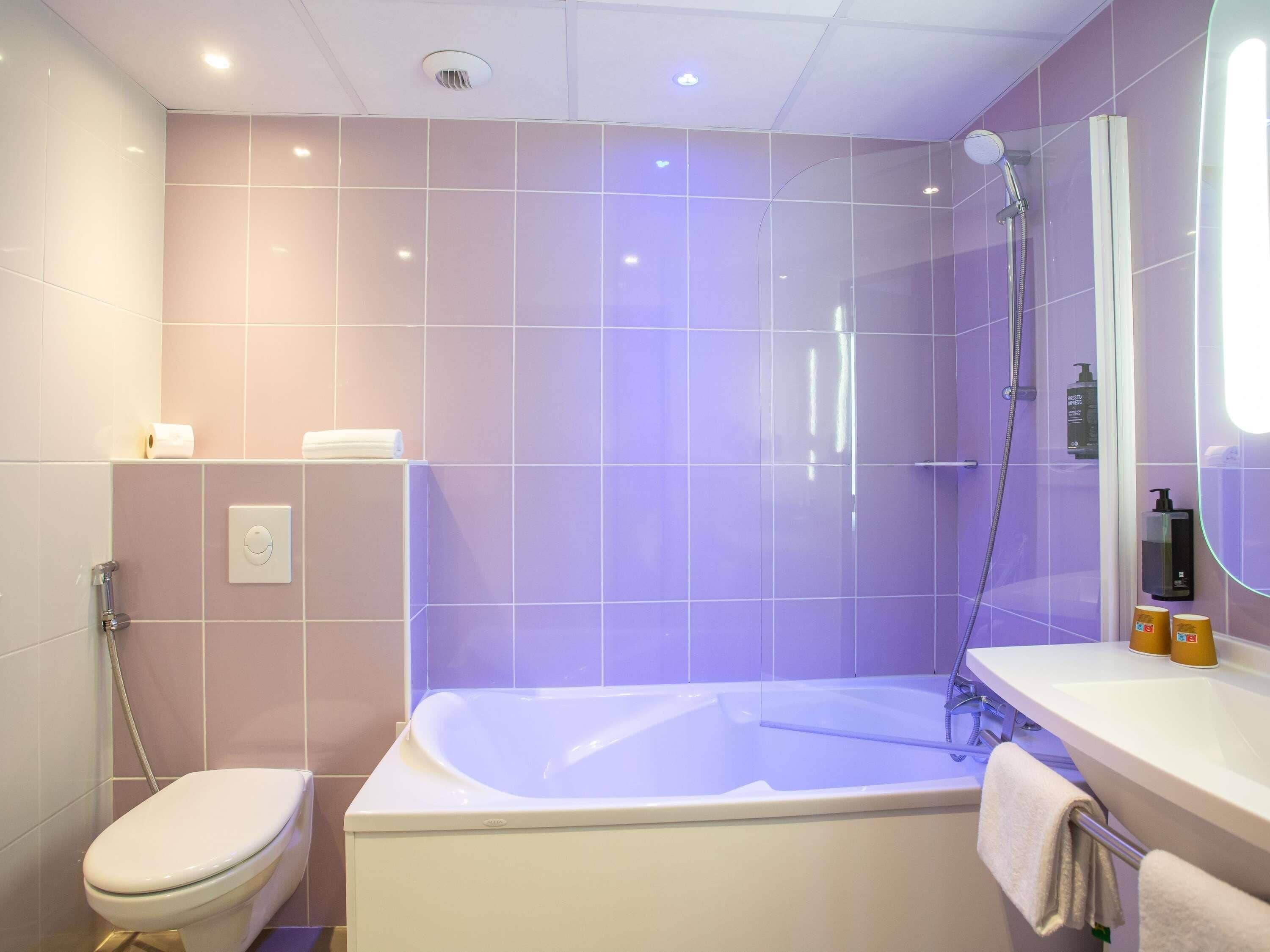 A modern bathroom with a bathtub, toilet, and shower.
