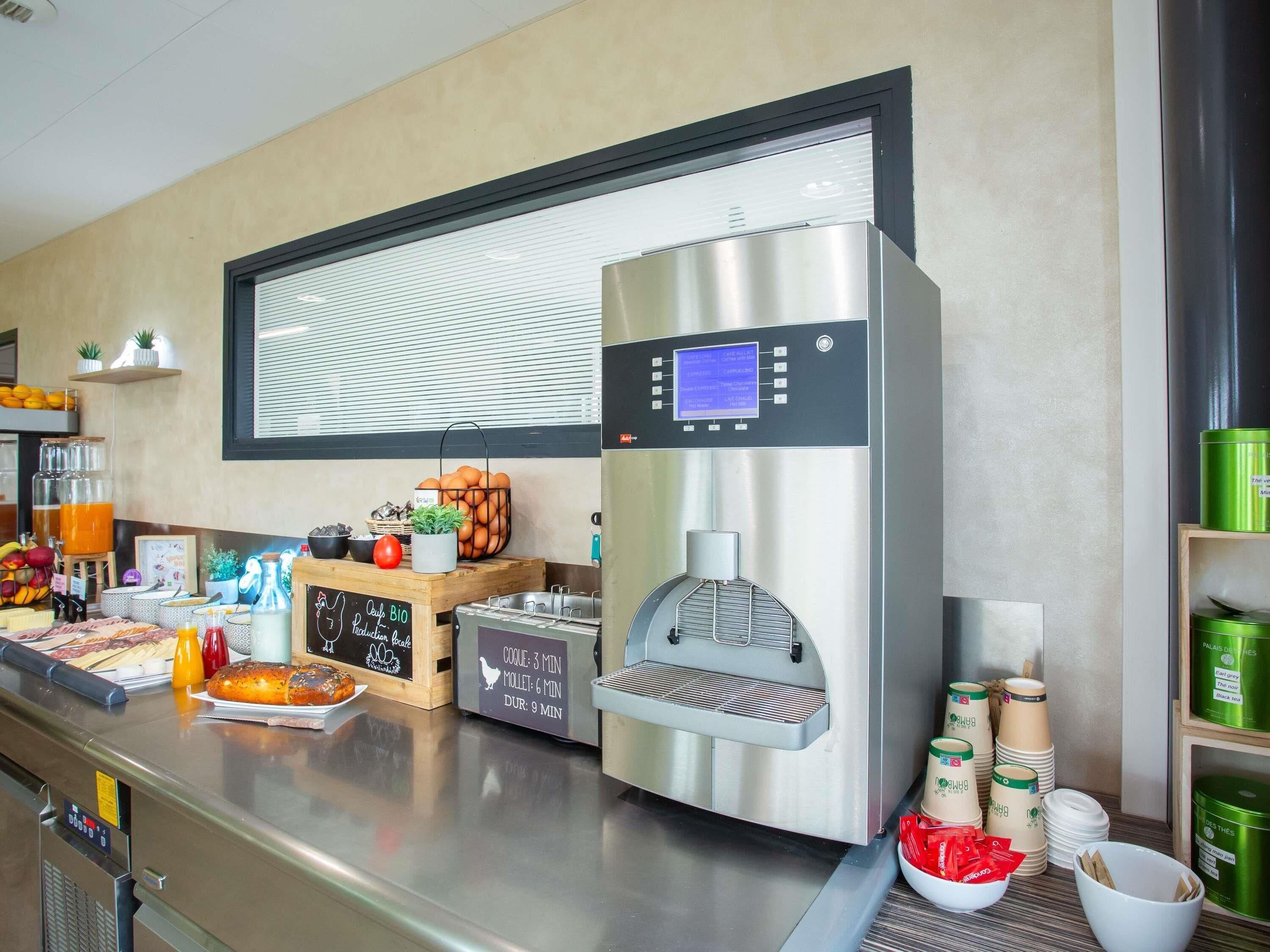 Un espace dédié au café, comprenant une machine à café, un tableau noir servant de menu, ainsi que divers tasses et récipients à café.