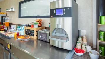 Un espace dédié au café, comprenant une machine à café, un tableau noir servant de menu, ainsi que divers tasses et récipients à café.