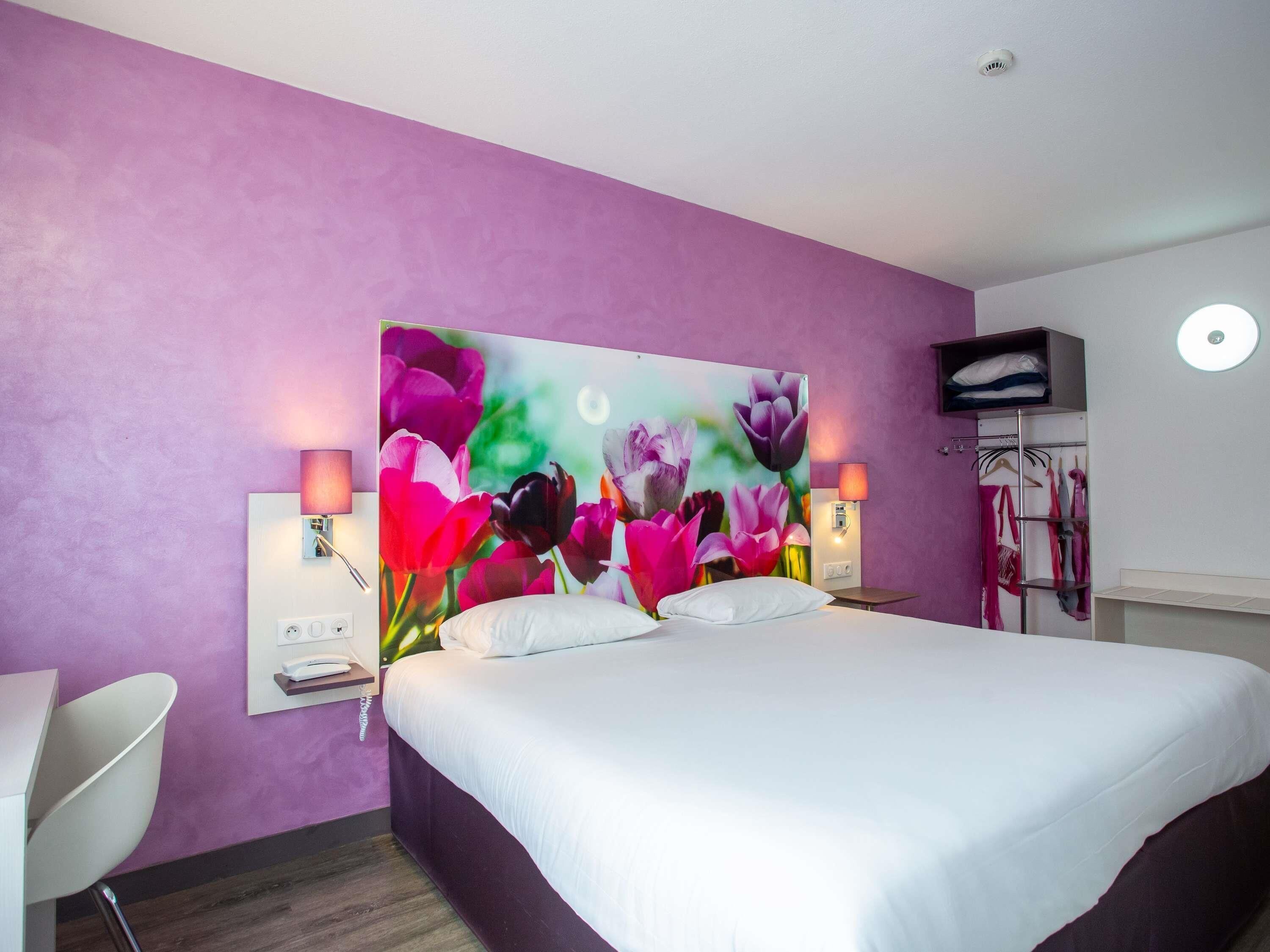 A bedroom with a large bed, two bedside lamps, a flat-screen TV, and a wardrobe with a mirror.