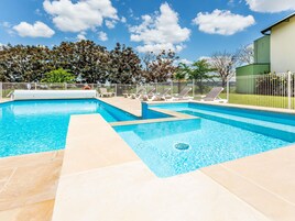 Una piscina al aire libre de temporada, sillones reclinables de piscina