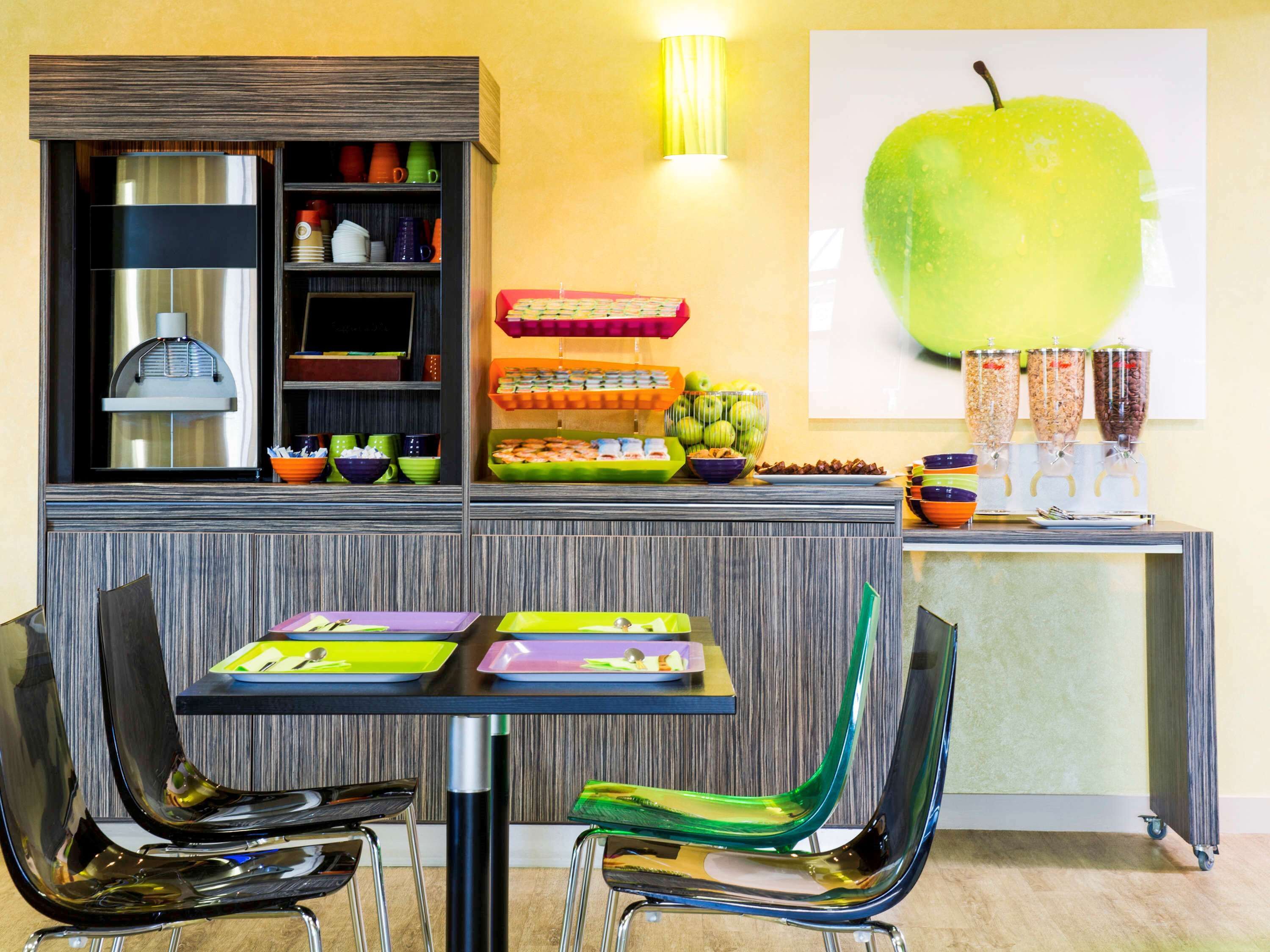 A modern kitchen area with a wooden cabinet, a fruit bowl, and a wall-mounted light fixture.