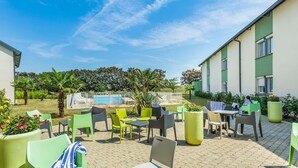 An outdoor patio with seating, a pool, and greenery. - ibis Styles Bourges (Bourges)