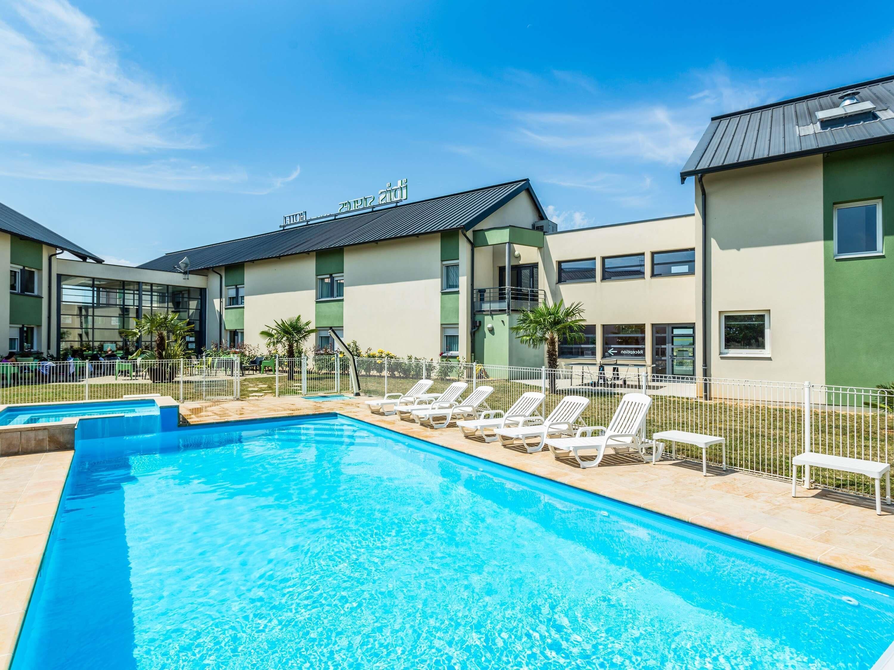 A swimming pool with lounge chairs and a building with a sign.