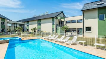 A swimming pool with lounge chairs and a building with a sign.