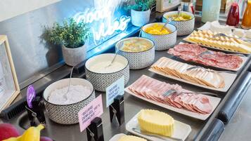 Un bufé con diferentes opciones de comida, incluyendo queso, carnes y frutas.
